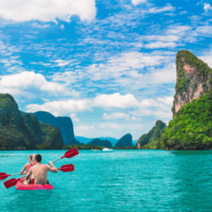 A couple kayaking in Ko Tapu, surrounded by towering limestone cliffs and clear waters.