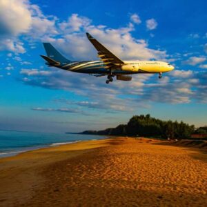 a plane flies over the beach in Phuket on its way in to land